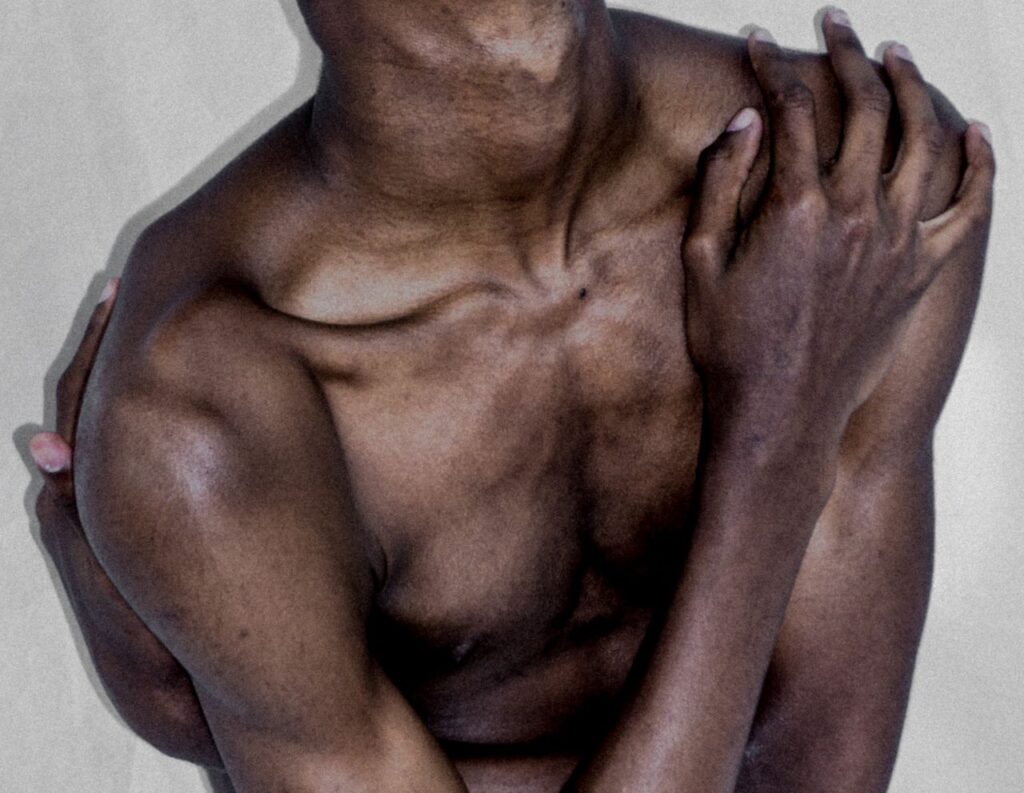 Close-up artistic portrait of a person embracing self, showcasing vulnerability and human form.